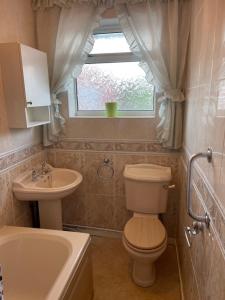baño con aseo y lavabo y ventana en Spacious 9 bed house in Mansfield Nottinghamshire en Mansfield