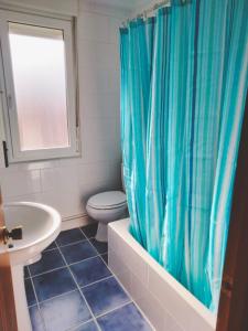 a bathroom with a blue shower curtain and a toilet at Solete in Suances