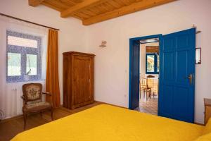 a bedroom with a yellow bed and a blue door at CSENDÜLŐ VENDÉGHÁZ in Noszvaj