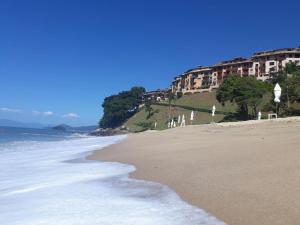 a beach with buildings on a hill next to the ocean at Apartamento a 50m da areia - Praia da Tabatinga in Caraguatatuba