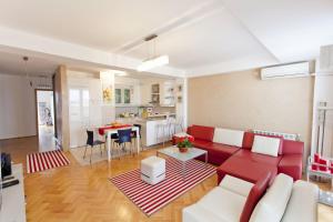 a living room with a red couch and a kitchen at Tina Apartments in Skopje