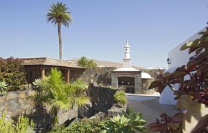a church with a palm tree and a building at Villa Remedios in Teguise