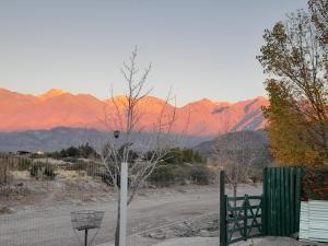 a fence and a tree with mountains in the background at Bella Vista in Potrerillos