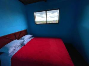 1 dormitorio con cama roja y ventana en Casa hospedaje Puyo, en Puyo