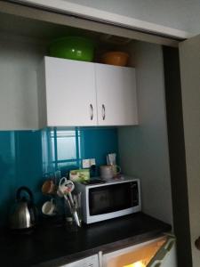 a kitchen with white cabinets and a microwave at Two rooms with one queen size bed in each room one bathroom for the two rooms in Mount Maunganui