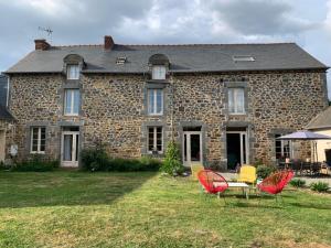 a stone house with chairs and a table in front of it at Le Logis de la Lettre in Tinténiac