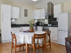 a kitchen with a table with chairs and white cabinets at Wellys Wallow in Saint Kew