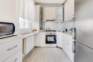 a white kitchen with white cabinets and a refrigerator at ARI Cherry Apartament with Balcony in Arad