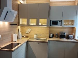 a kitchen with white cabinets and a sink at Havel Apartment in Opole +25 photos