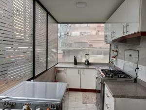 cocina con fregadero y fogones en Elegante departamento, lavadora, sauna, jacuzzi, en Quito