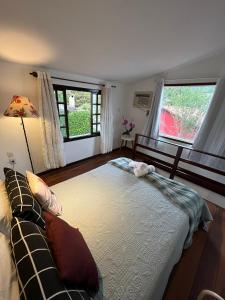 a bedroom with a large bed and two windows at Vila Noel Centro in Penedo