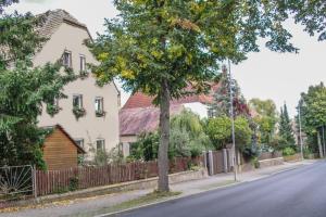 a street with houses and a tree on the side of the road at Pension Muldental Großbothen in Grimma