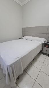 a large white bed in a room with a tiled floor at Apartamento: Acomodação mobiliada e completa in Blumenau