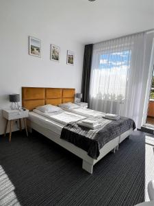 Un dormitorio con una cama grande y una ventana en Apartamenty Planeta Mielno, en Mielno