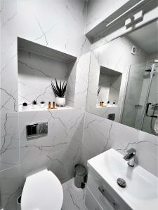 Baño blanco con aseo y lavamanos en Apartamenty Planeta Mielno, en Mielno