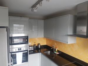 a kitchen with white cabinets and silver appliances at Beautiful 3-bedroom flat with stunning views in London