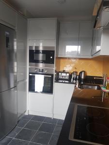 a kitchen with white cabinets and black appliances at Beautiful 3-bedroom flat with stunning views in London