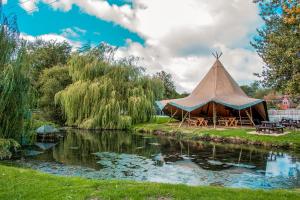 a teepee tent next to a river with trees at The George Inn in Warminster