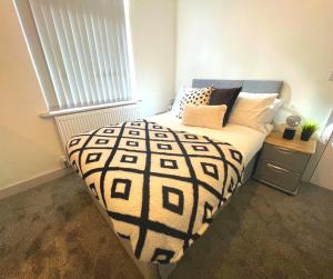 a bedroom with a bed with a black and white comforter at SA Stays in Wigan
