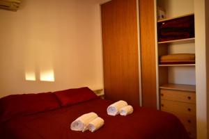 1 dormitorio con 1 cama roja y 2 toallas en El Luminoso 11 en La Plata