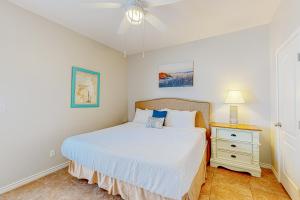 a bedroom with a bed and a nightstand with a white bed sidx sidx sidx at Morgan Shores in Port Aransas