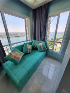 ein grünes Sofa in einem Zimmer mit großen Fenstern in der Unterkunft Stunning river view from a spacious 3-Bedroom Apt. in Kairo