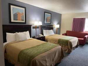 a hotel room with two beds and a chair at Village Inn Green Bay in Green Bay