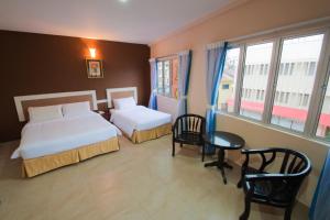 um quarto de hotel com duas camas e uma mesa e cadeiras em CK Hotel em Malaca
