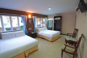 um quarto de hotel com duas camas e uma cadeira em CK Hotel em Malaca