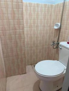 uma casa de banho com um WC e uma parede em azulejo em 4C’s Room Rental, Apartments, Hotel and Transient em Calapan