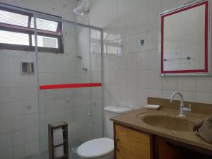 a bathroom with a sink and a toilet and a mirror at Chalé do Tio Beto - Caraguatatuba in Caraguatatuba