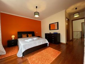 1 dormitorio con 1 cama con pared de color naranja en Briola by AnaLodges, en São Vicente