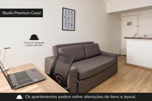 聖保羅的住宿－NewCiti Itaim by Charlie，一间配有沙发和一张带笔记本电脑的桌子的房间