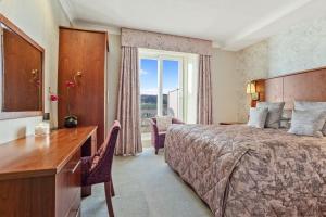 a hotel room with a bed and a desk and a window at Ambleside Salutation Hotel & Spa, World Hotel Distinctive in Ambleside