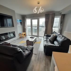 a living room with two leather couches and a tv at Atlantic Port Retreat in Portstewart