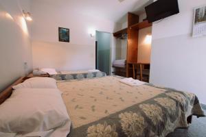 una camera da letto con due letti e una TV a parete di Das Heim Hotel ad Asunción