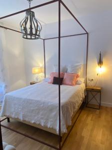 ein Schlafzimmer mit einem Himmelbett mit weißer Bettwäsche und rosa Kissen in der Unterkunft Luz Los Romeros in Los Romeros