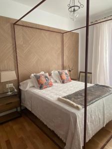 ein Schlafzimmer mit einem Himmelbett mit weißer Bettwäsche und Kissen in der Unterkunft Luz Los Romeros in Los Romeros