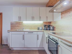 a white kitchen with white cabinets and a sink at Glonersbühelhof Top 2 in Westendorf