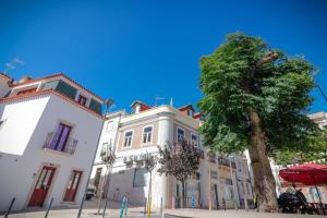 uma árvore em frente a um edifício branco em Refúgio do Paixão em Sesimbra