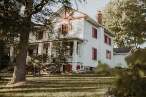 a white house with red shutters and a tree at Almatoit in Alma