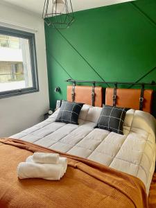 een slaapkamer met een groot bed met een groene muur bij TREJO Nueva Córdoba - A metros del Hospital Allende y Oulton in Cordoba