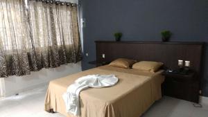 a bedroom with a bed with a white robe on it at Hotel Peccato Originale in Tuxtla Gutiérrez