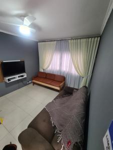 a living room with a couch and a television at Casa grande e confortável até 16 pessoas com churrasqueira e garagem para 8 carros in Praia Grande