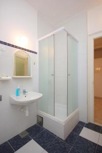 ein weißes Bad mit einem Waschbecken und einer Dusche in der Unterkunft Apartments by the sea Komiza, Vis - 8533 in Komiža