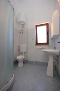 a bathroom with a toilet and a sink and a window at Apartment Ilovik 8069a in Ilovik