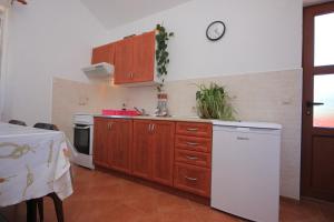 cocina con armarios de madera y nevera blanca en Apartment Ilovik 8069a, en Ilovik