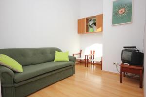 ein Wohnzimmer mit einem grünen Sofa und einem TV in der Unterkunft Apartments by the sea Ilovik, Losinj - 8069 in Ilovik