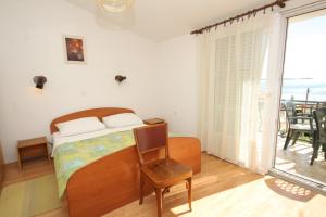 a bedroom with a bed and a chair and a window at Triple Room Pasman 8223e in Pašman