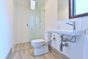 a white bathroom with a toilet and a sink at Summerfield Cottage Hunter Valley in Branxton